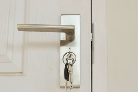 Key insert and hold in metallic knob on white door horizontal, architecture by Locksmith