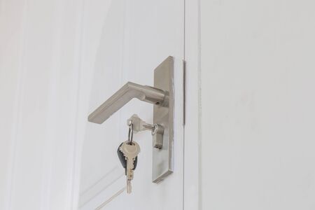 Key insert and hold in metallic knob on white door horizontal as locksmith concept.の写真素材