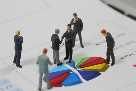 Top view selective focus of miniature business man handshake on colorful circle chart background as commitment and investment concept.の写真素材