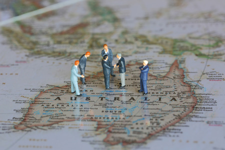 Selective focus of miniature businessman handshake on Australia map background as commitment,...
