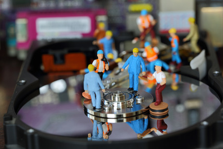 Selective focus of miniature engineer and worker discuss in job repair  harddisk (hard disk) and fixed problem harddisk (hard disk) of Personal computer (PC) as business and industrial concept.の写真素材