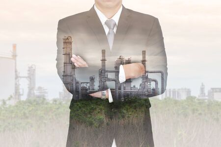 Double exposure of business man arms crossed, electric generating factory at evening as vision of leader,Industrial and Technology concept.の写真素材