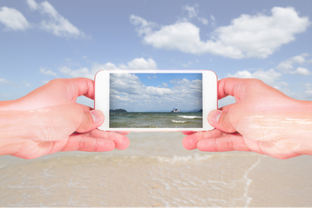 double exposure of man use two hand hold smart phone, tablet,cellphone, beach and sea view as...