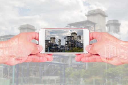 double exposure of man use two hand hold smart phone, tablet,cellphone, Electric Generating Factory and Power Reactor as Energy, communication and technology concept.の写真素材
