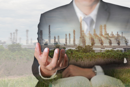 Double exposure of business man hand hold and oil refinery industry plant, Electric Generating Factory and sunset in the evening as Energy and Business success concept.の写真素材