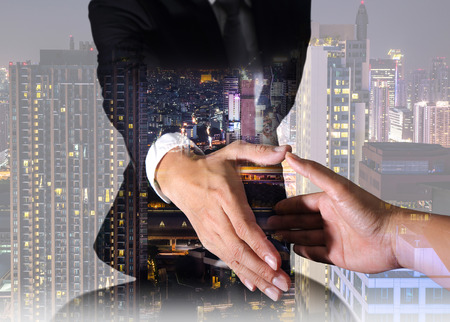 Businessman will handshaking for business relationship, city at night as Congratulation, Commitment and Partnership concept.の写真素材