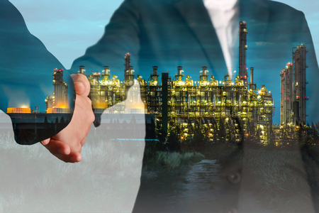 Double exposure of handshake and gas and oil refinery industry plant at twilight as commitment of energy concept.の写真素材