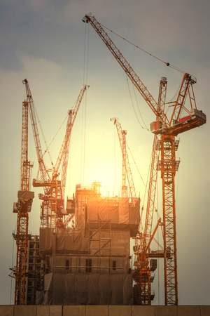 construction crane, building and sunset in the eveningの写真素材
