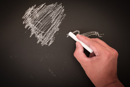 hand to draw something on blackboard with chalkの写真素材