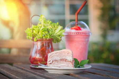 Delicious chocolate cake and blur strawberry beverage on the wooden table with outdoor lightingの写真素材