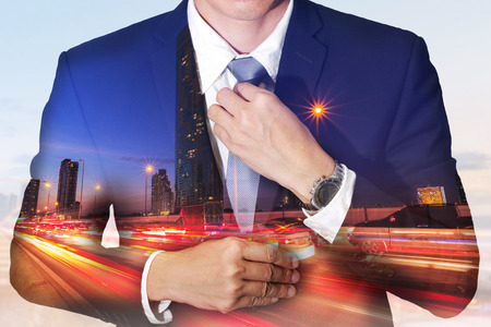 Double exposure of businessman held necktie dress to look good, light trails on street, urban and city in the night as get ready of business concept.の写真素材