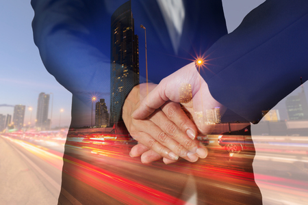 Double exposure of handshake and light trails on the street and urban at dusk, night as business, partnership and commitment concept.の写真素材