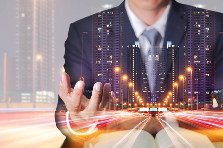 Double exposure of businessman hand hold, light trails on the street and urban in the night as business control concept.の写真素材