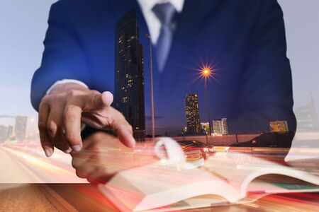 Double exposure of businessman pointing and light trails on the street and urban at dusk, night as business target concept.の写真素材