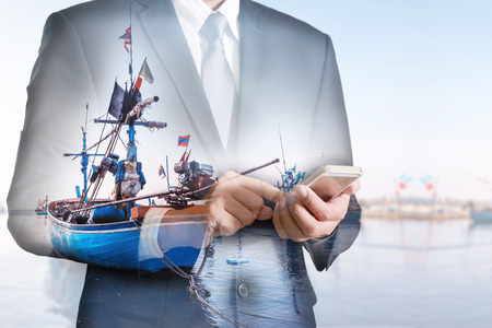 Double exposure of business man hand hold and touch screen smart phone, mobile, fishing boat and sea as business, technology, communication and marine industry concept.の写真素材