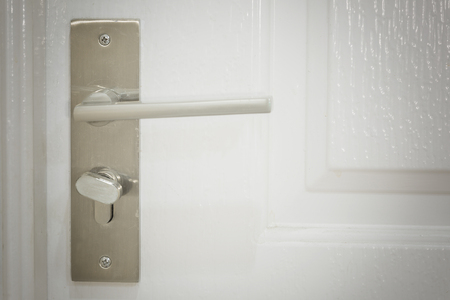 closeup view metallic knob on white door horizontal as locksmith conceptの写真素材