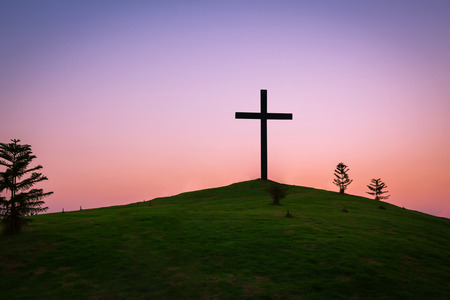 The cross is buried on a grassy hill and meadow in the twilight, abstract nature background as Christianity concept.の写真素材
