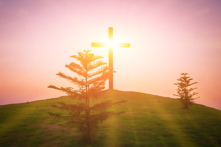 Sunset over on the cross is buried on a grassy hill and meadow, abstract nature background as Christianity concept.の写真素材