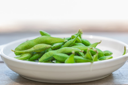 Soybean pods on white dish in the nature backgroundの写真素材