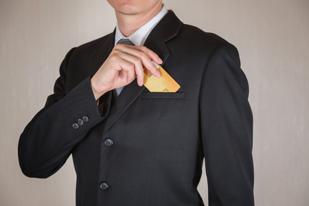 Businessman put golden credit card in his suit pocket as business and financial flexibility concept.の写真素材