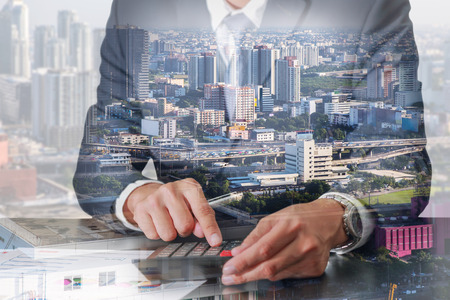 Double exposure of businessman working with calculator, cityscape and traffic city in the foggy morning as business, worker, Commitment and Calculation conceptの写真素材