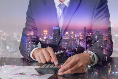Businessman working with calculator, cityscape and urban in the night or twilight as business, Worker, intention, Commitment and Calculation conceptの写真素材