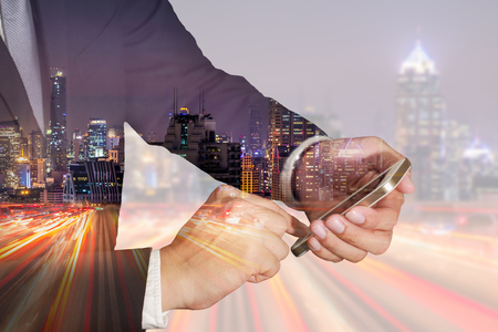 Double exposure of businessman use smartphone, light trails on the street and city in the night as business, Technology, telecommunication and Communication concept.の写真素材