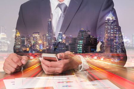Double exposure of businessman working with smartphone, light trails on the street, urban and city in the night as business, technology and communication concept.の写真素材