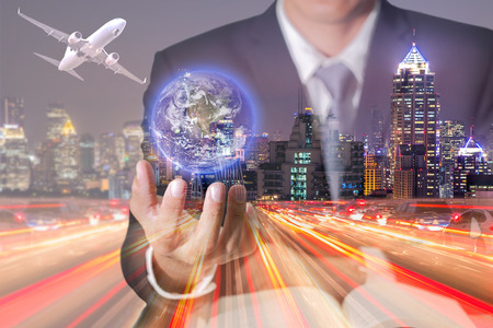 Double exposure of businessman hand hold virtual glowing world, light trails on street and city in the night as business control and globalization concept.の写真素材
