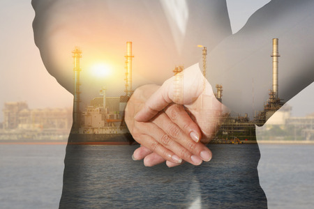 Double exposure of handshake, oil fuel, Electric generating factory or plant at the river with sunset  as business, commitment, congratulation, welcome, industrial and energy conceptの写真素材