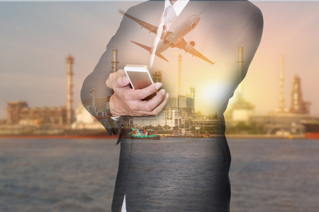 Double exposure of businessman hand hold smartphone, airplane , oil fuel, Electric generating factory or plant at sunset as business, technology, communication, industrial and energy conceptの写真素材