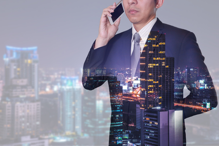 Double exposure of businessman calling with smartphone, street, city and urban in the night as business, technology and telecommunication concept.の写真素材