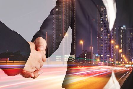 Double exposure of handshake, light trails on the street and urban in the night as business, relationship, partnership and commitment concept.の写真素材