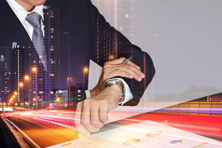 Double exposure of businessman take time in appointments, light trails on the street and urban in the night as business and punctual concept.の写真素材