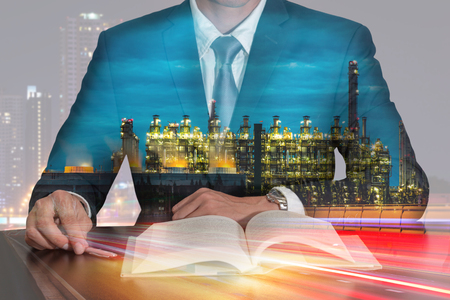 Double exposure of businessman sitting at meeting room to open the book, light trails on the street and urban, Electric generating factory industry in night as energy, business and Learning concept.の写真素材