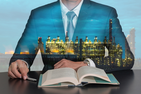 Double exposure of businessman sitting at meeting room to open the book and electric generating factory industry in the night as energy, business and Learning concept.の写真素材