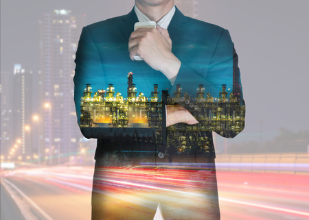 Double exposure of businessman stand up and think idea about business, electric generating factory industry and light trails on night street as business, energy and thoughtful concept.の写真素材