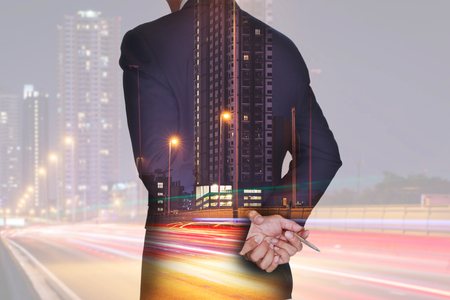 Double exposure of businessman think and analyze the work, light trails on the street and urban in the night as business and vision of leader conceptの写真素材