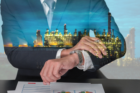Double exposure of businessman look the watch and Electric generating factory industry in the night as industrial, appointment and business concept.の写真素材