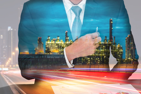 Double exposure of businessman holding a pen on the pocket, light trails on the street and urban, Electric generating factory industry in the night as energy, business and analysis conceptの写真素材