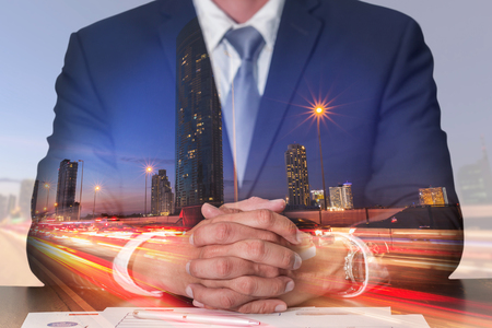 Double exposure of businessman fingers crossed and sit down, light trails on the street and urban at dusk, night as meeting, commitment and business concept.の写真素材
