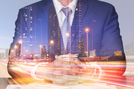 Double exposure of businessman fingers crossed and sit down, light trails on the street and urban at dusk, night as meeting, commitment and business concept.の写真素材