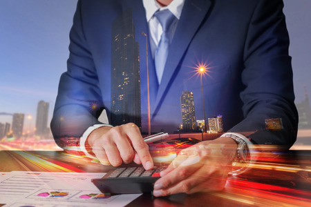 Double exposure of businessman working with calculator and light trails on the street and urban at dusk, night as Worker, Commitment and Calculation conceptの写真素材