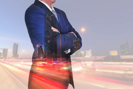 Double exposure of Businessman arms crossed and stand up and light trails on the street and urban at dusk, night as business and thinking vision of leader concept.の写真素材