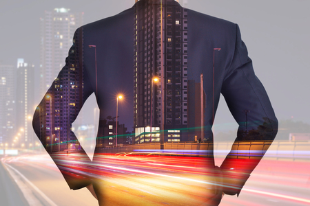 A back turned businessman, light trails on the street and urban in the night as business and vision of leader conceptの写真素材