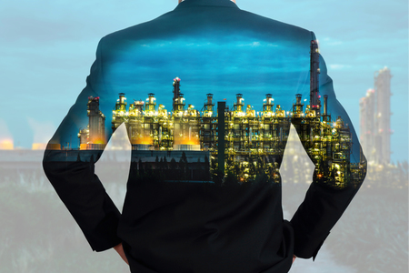 A back turned businessman and Electric generating factory industry in the night as business vision of leader and energy conceptの写真素材