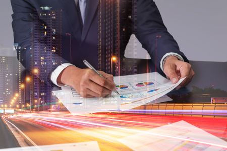 Double exposure of businessman review charts, light trails on the street and urban in the night as business and analysis concept.の写真素材