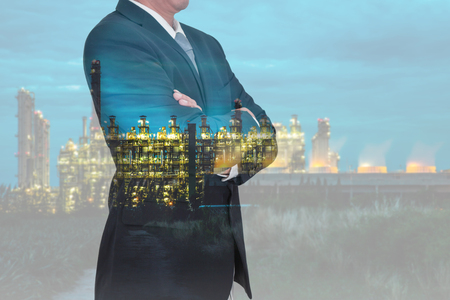 Double exposure of Businessman arms crossed and stand up and Electric generating factory industry in the night as business, thinking vision of leader and energy concept.の写真素材
