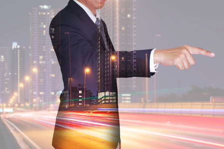 Double exposure of businessman finger point virtual target, light trails on the street and urban in the night as business and target conceptの写真素材