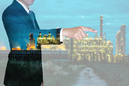 Double exposure of businessman finger point virtual target, electric generating factory industry at night as energy, business and target concept.の写真素材